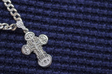 Fototapeta na wymiar Silver cross on a blue background. Symbol of faith. Christianity