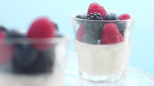 woman's hand put a glass with panna cotta with berries to table