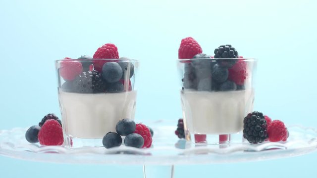 two glasses with dessert turning on a crystal plate decorated with berries