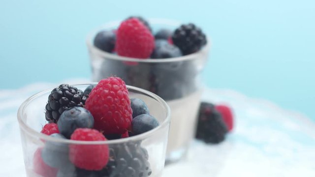 glasses full of yogurt and berries on a crystal plate turning on it's axis in studio minimalist clip