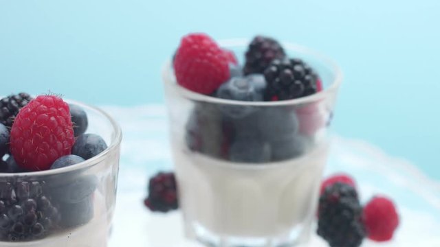 glasses full of yogurt and berries on a crystal plate turning on it's axis in studio minimalist clip