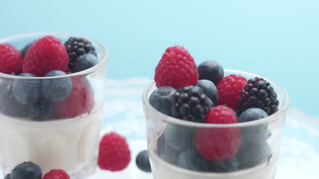 glasses full of yogurt and berries on a crystal plate turning on it's axis in studio minimalist clip