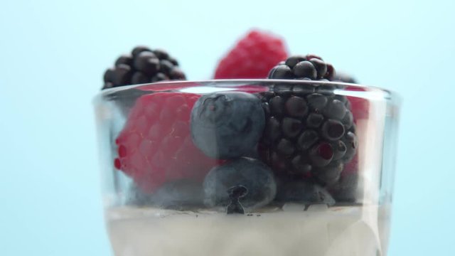 closeup of berries decoration of dessert in transparent glass full of panna cotta or greek yogurt