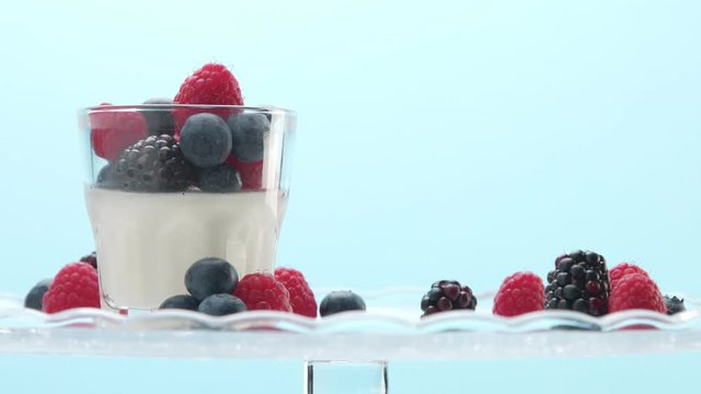 woman hand serve putting on a crystal plate glass with greek yogurt with berries