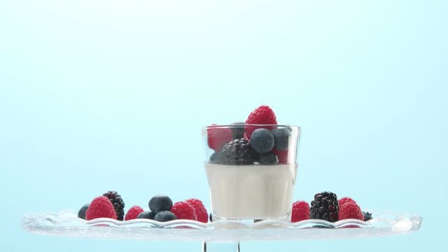 woman hand serve putting on a crystal plate glass with greek yogurt with berries