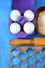 Eggs, flour and kitchen utensils for cooking homemade dumplings on blue background