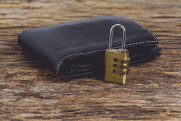 wallet with metal security lock with pass-code or password on wooden table.