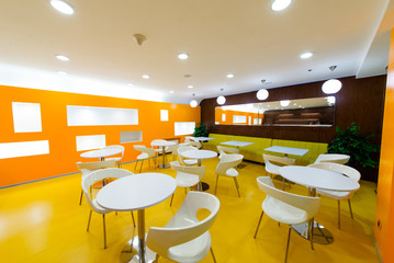 Interior cafe. White chairs and tables in the orange and yellow room.