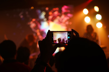 Fototapeta na wymiar Audience keep taking photo and video at concert with their cellphone focus on the screen with blur background