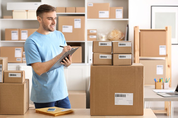 Young man preparing parcels for shipment to client in home office