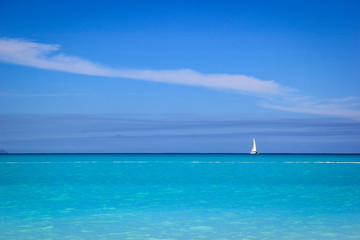 Fototapeta na wymiar White sailboat against blue sky and sea, Antigua, Antigua and Baruda.