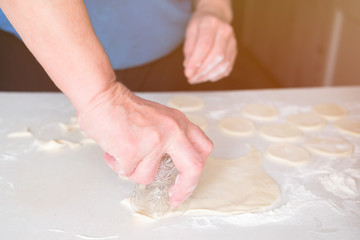 Obraz na płótnie Canvas Hands of woman knead the dough on a table, selective focus.