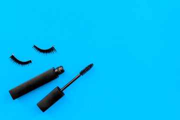 Basic products for eyelashes makeup. Mascara and false eyelashes on blue background top view copy space