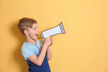 Cute little boy with paper megaphone on color background