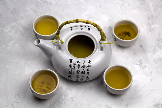 top view teapot and tea bowls with hieroglyphs concrete backgroun