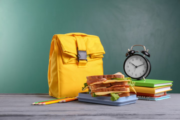 Composition with lunch box and food on table against blackboard
