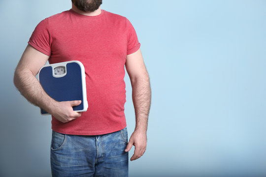 Overweight Man With Scale On Color Background