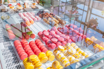 Assortment of colorful macaroons on cafe showcase. Variety of macaron flavours. Sweet almond cakes in store.