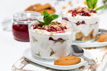 dessert in a glass with biscuits, cream and jam, closeup