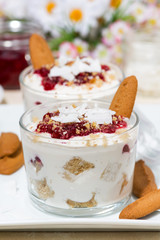 dessert in a glass with cookies, cream and jam, vertical closeup