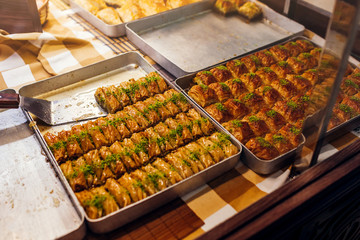 Assortment of Turkish baklava with pistachio on cafe showcase. Sweet baklawa on tray in store. Arabic dessert.