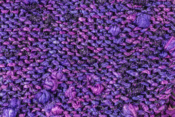 knitted fabric background in shades of pink and purple with knobs