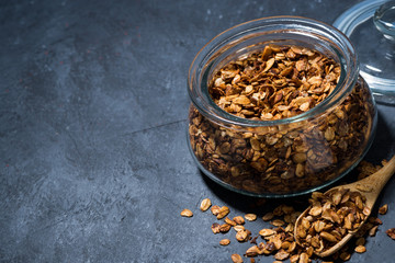 homemade baked granola in a glass jar on dark background