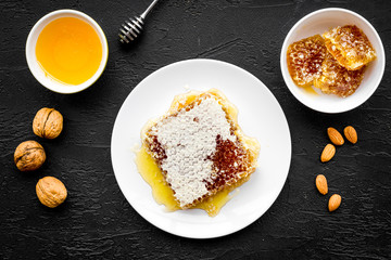 Fresh honey as dessert. Honey in bowl, honeycomb, nuts on black table top view