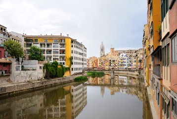 Fototapeta na wymiar Colorful houses, reflected in the water of the river Onyar. View from the Red iron bridge or Girona Eiffel Bridge (Pont de les Peixateries velles). The historic Jewish quarter in Girona, Spain. 
