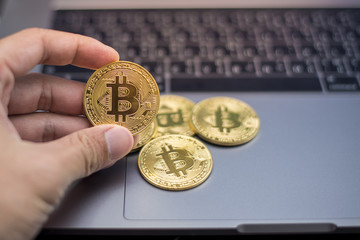 male hand holding  bitcoin on a laptop background.