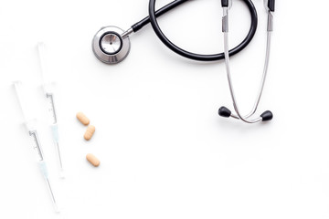 Medical examination and treatment concept. Stethoscope, syringe, pills on white background top view copy space