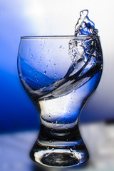 Splash water in a glass in blue tones