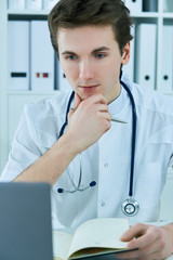 Portrait of doctor working on his computer in medical office.