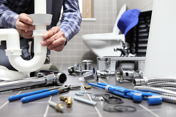 plumber at work in a bathroom, plumbing repair service, assemble and install concept - obrazy, fototapety, plakaty