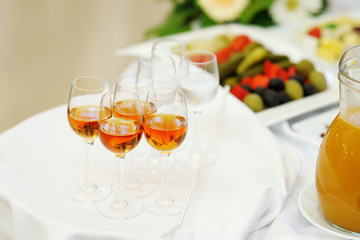 Glasses with alcoholic drinks stand on the white tray. Welcome drink.
