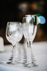 Empty glass for wine and champagne stand on white table. Close up. Empty glasses for elite drinks stand in two rows.