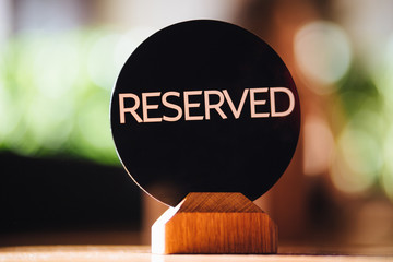 Booking and reservation concept. Round plate with written word Reserved, shows that place in...