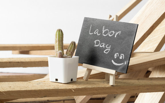 Happy International Workers' day and Happy Labor day concept. Small chalk board with text Labor Day with cactus and wooden pallet background on white background. - Powered by Adobe