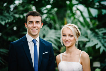 Portrait the groom and the bride on the background of greenery. Wedding ceremony in Botanical green...