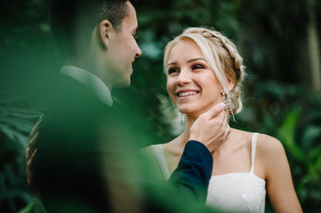 Portrait the groom and the bride on the background of greenery. Wedding ceremony in Botanical green...