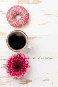 Coffee cup, donut and gerbera flower