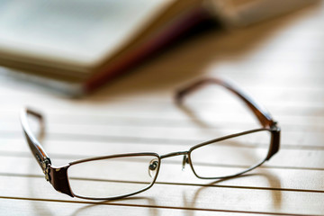 Open book and glasses on wooden table close