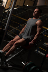 Sports concept. Strong young man in a t-shirt and shorts doing exercises on the simulators in the gym looking to the side