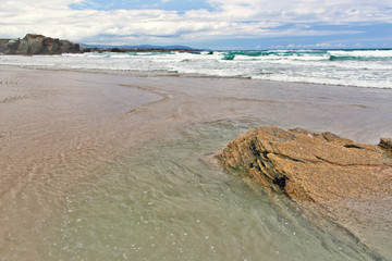 Large stones on the sandy beach by the sea