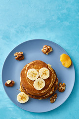 Pile of homemade pancakes with honey and walnuts on rustic wooden background, selective focus