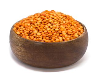 Red raw lentils in a wooden bowl. Isolated on white background