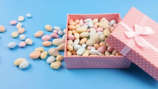 Nice pastel color candy or stone in gift pink box on blye surface.