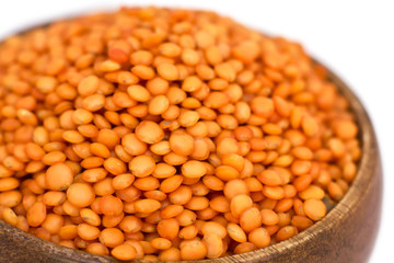Red raw lentils in a wooden bowl. Isolated on white background