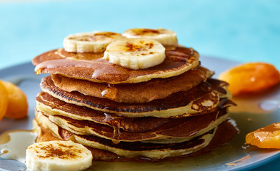 Pile of homemade pancakes with honey and walnuts on rustic wooden background, selective focus