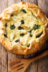 Homemade open savory pie with artichokes, cheese and spinach close-up. Vertical top view